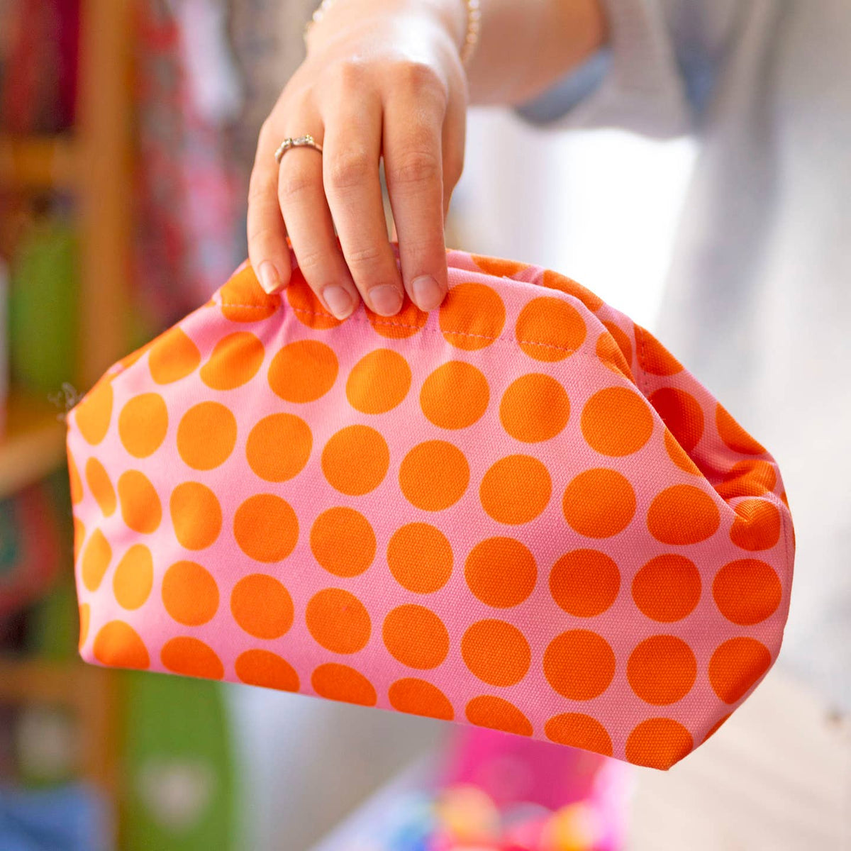 Bright pink clutch with bold orange polka dots, shown close up to highlight its fun, colourful design.