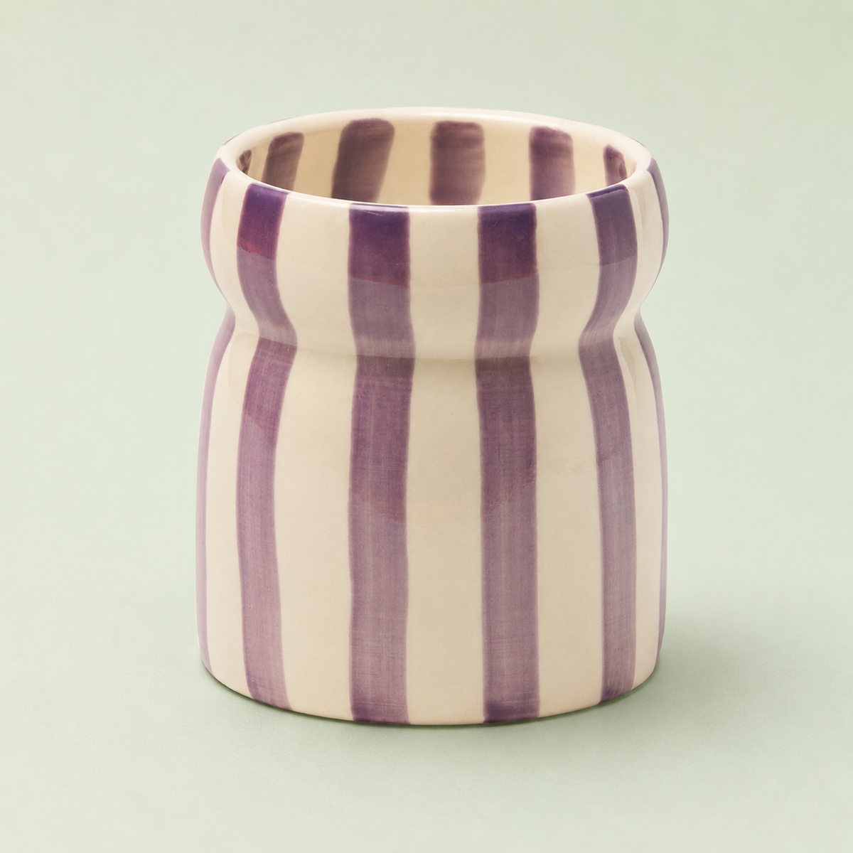 Hand painted purple and cream striped Waikiki Waters ceramic candle with distinctive pinched shape.