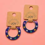 Pair of navy floral beaded hoop earrings displayed on Pocketful of JOY jewellery cards.