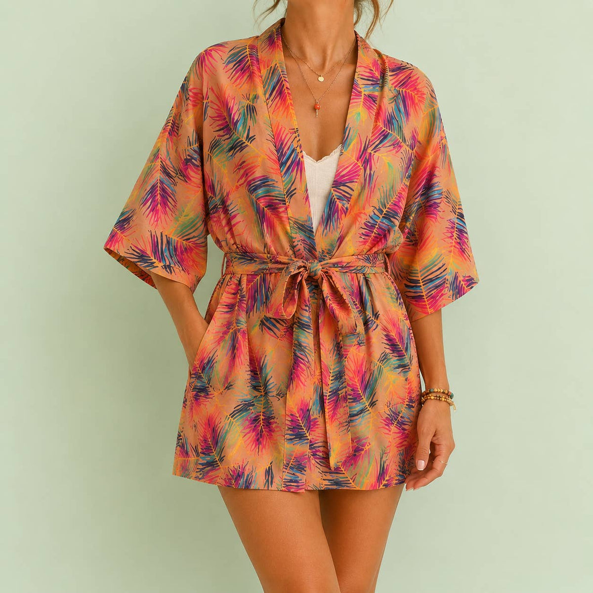 Colourful peach kimono robe with a vibrant tropical leaf print, wide sleeves and matching tie belt, styled for a joyful relaxed look.