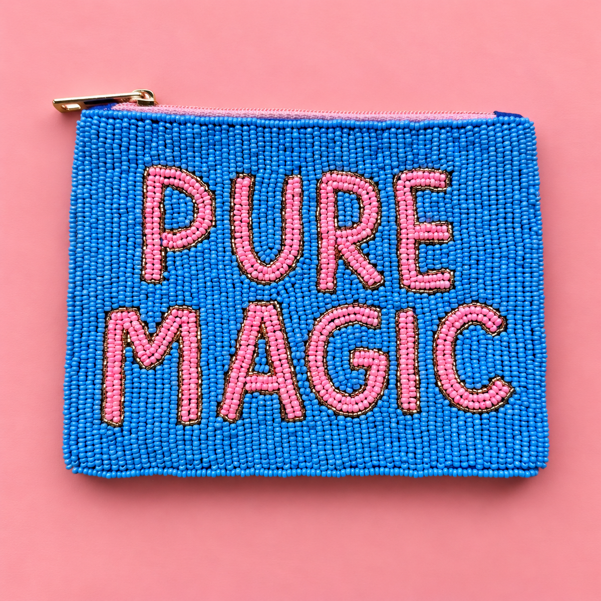 A rectangular blue beaded pouch with a gold zipper and the words 'PURE MAGIC' in pink beaded letters, displayed on a solid pink background.