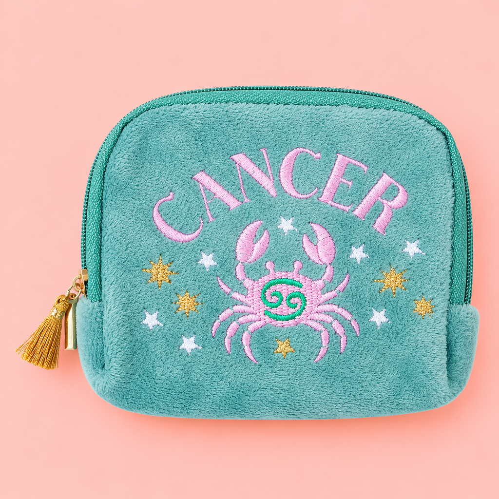 Teal Cancer velvet pouch with pink crab and colourful star embroidery on a soft pink background.