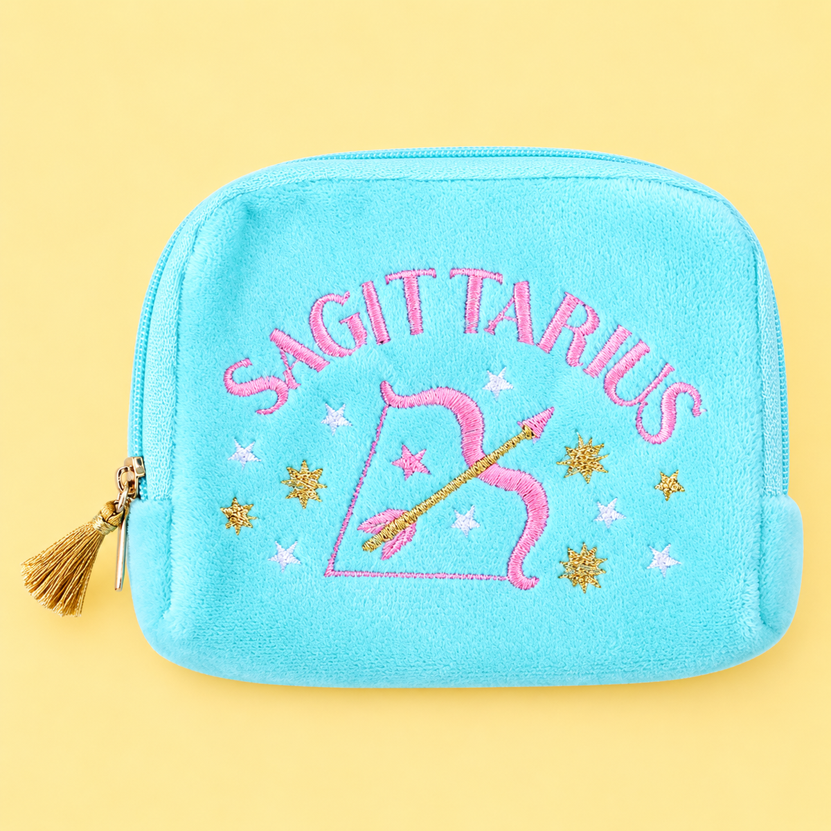 Turquoise velvet Sagittarius pouch with colourful embroidered stars, bow and arrow design and gold tassel zip on yellow background.