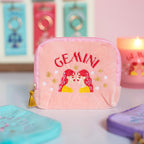 Pink velvet Gemini zodiac pouch with red and yellow embroidered twins, gold stars and gold tassel zip.