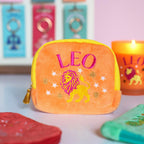 Peach orange velvet Leo zodiac pouch with hot pink and yellow embroidered lion, stars and gold tassel zip.