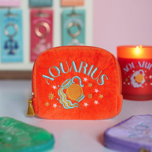 Orange Aquarius velvet pouch with colourful embroidered zodiac design displayed with matching candle and accessories.