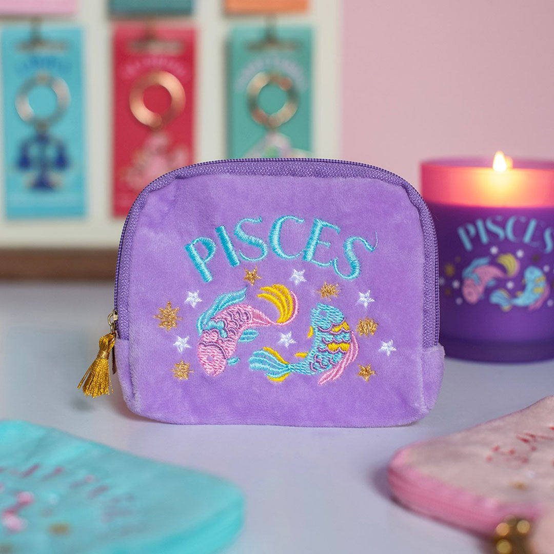 Lilac Pisces velvet pouch with colourful fish embroidery displayed alongside matching zodiac candle and accessories.