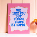Colourful We Like You But Please Leave By 10PM A5 print with bold blue lettering and a bright pink border.