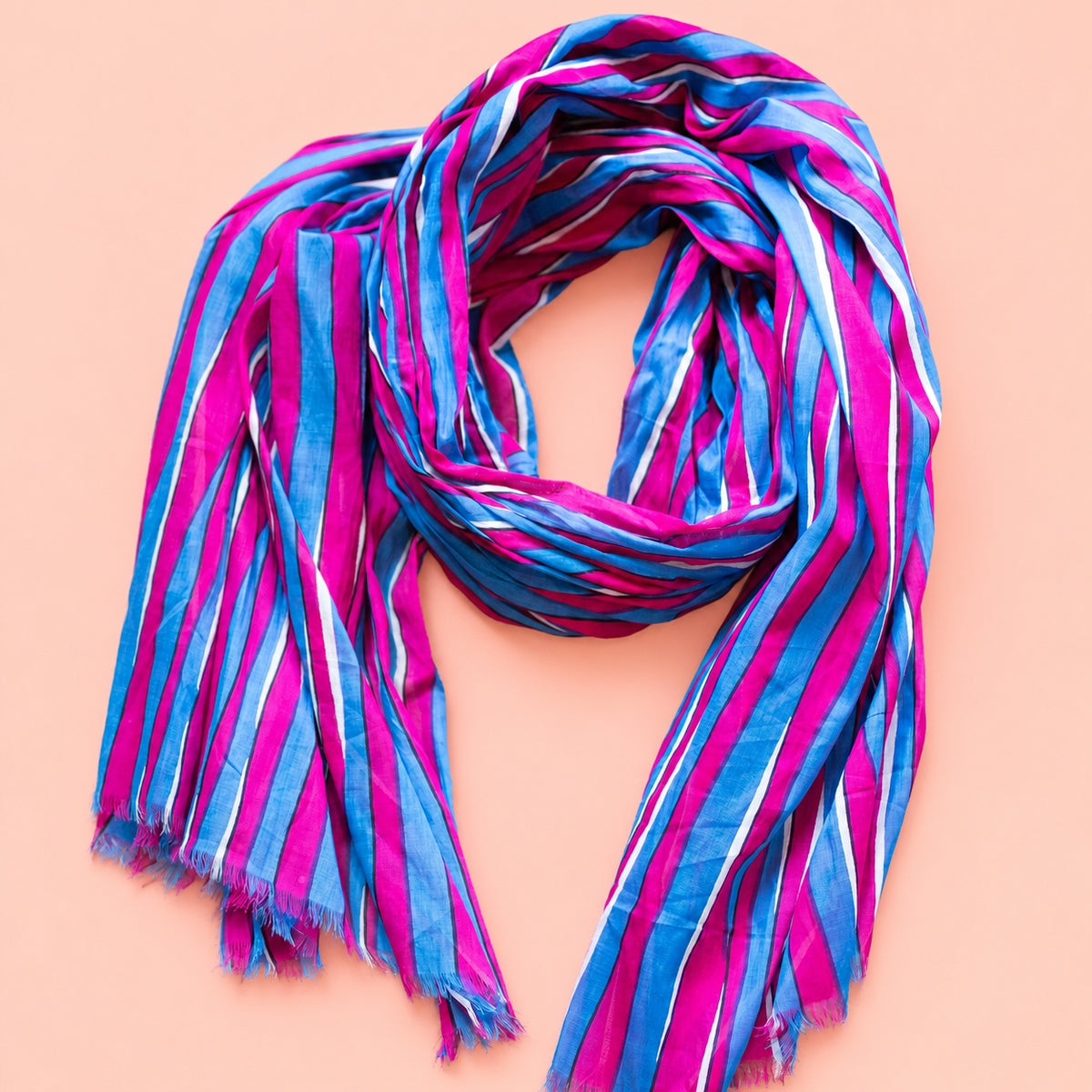Joyful pink, blue and white striped cotton scarf loosely styled to show its vibrant colours and soft frayed edges.