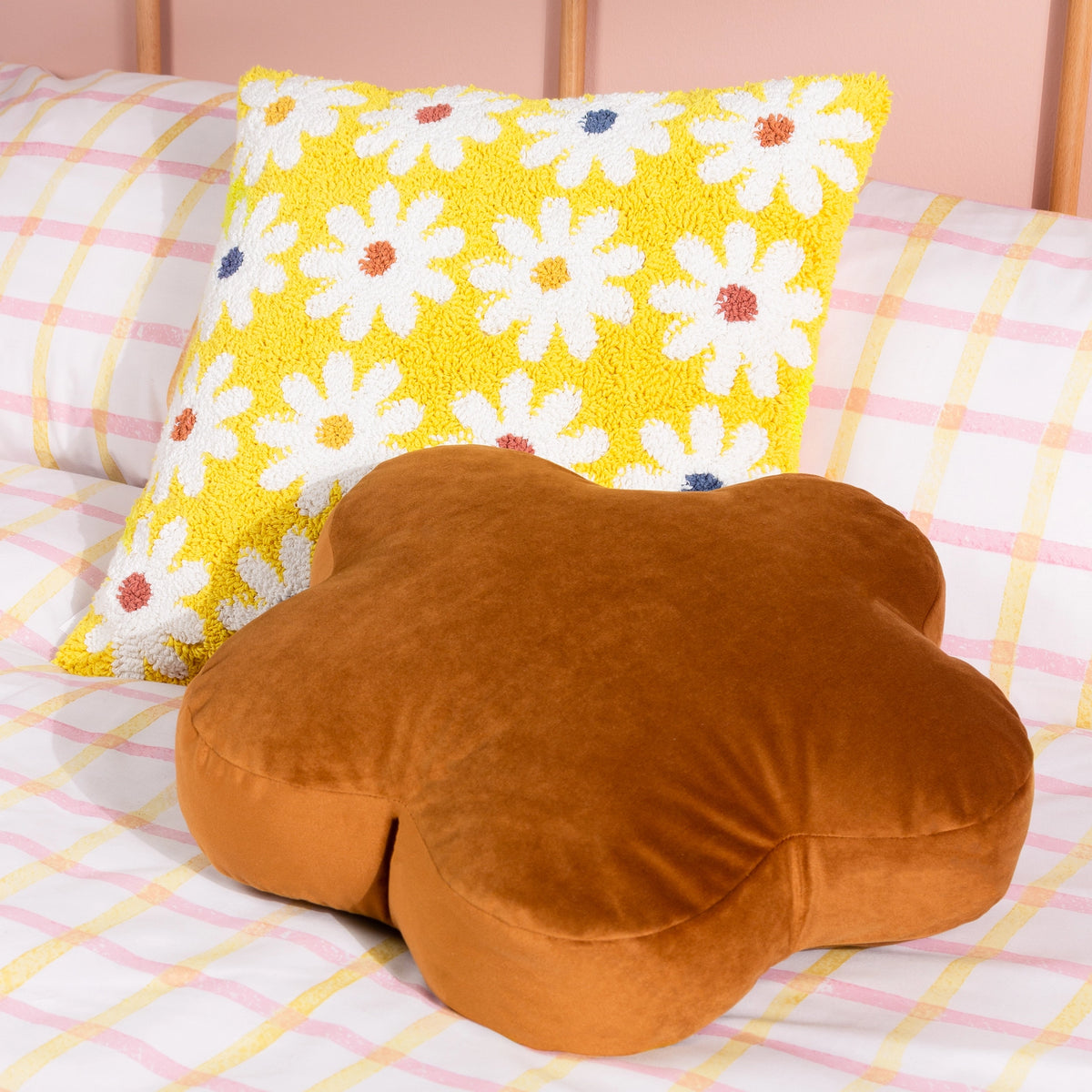 Yellow daisy tufted cushion styled on a checked bed with a large brown flower shaped cushion.