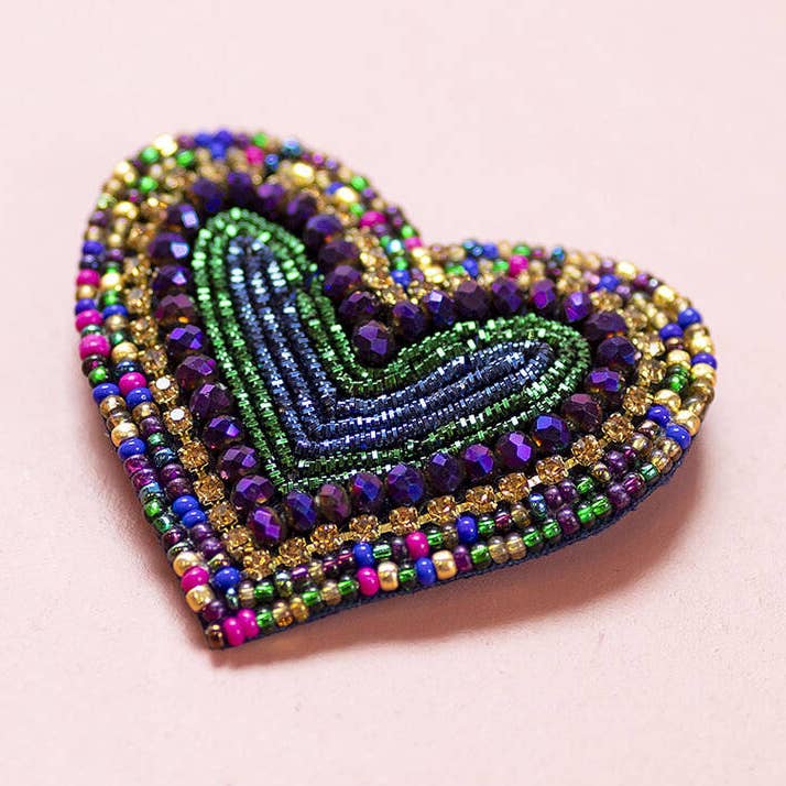 Purple and green heart shaped brooch with layered blue, gold and multicoloured beadwork.