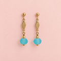 Pair of one of a kind gold plated drop earrings with geometric details and frosted aqua blue faceted glass beads on a pale pink background.