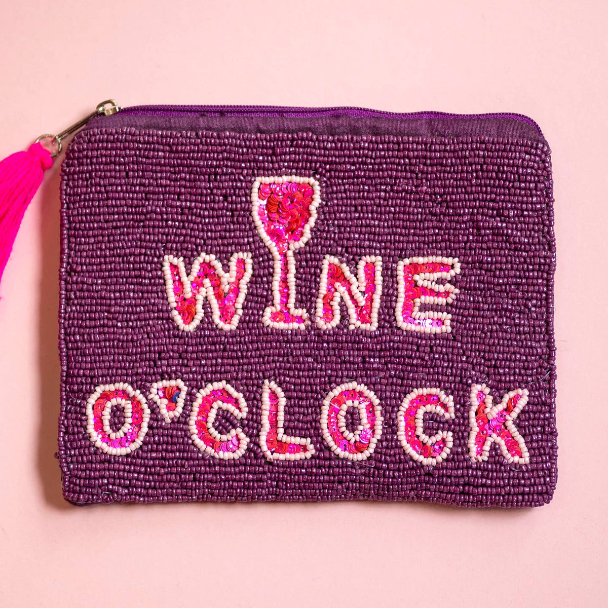 Purple beaded pouch with pink and white ‘WINE O’CLOCK’ lettering, wine glass motif and bright pink tassel.