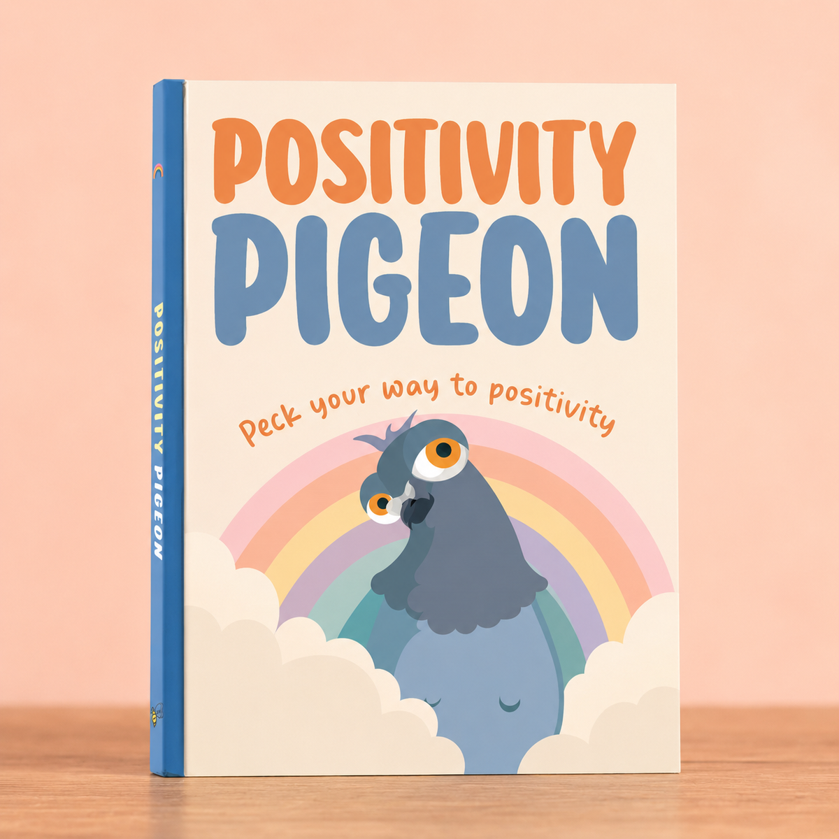 Positivity Pigeon colourful hardback gift book with rainbow and illustrated blue pigeon on the cover.