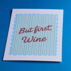 But First Wine A5 art print with red script and aqua striped design, photographed on a vivid blue background.