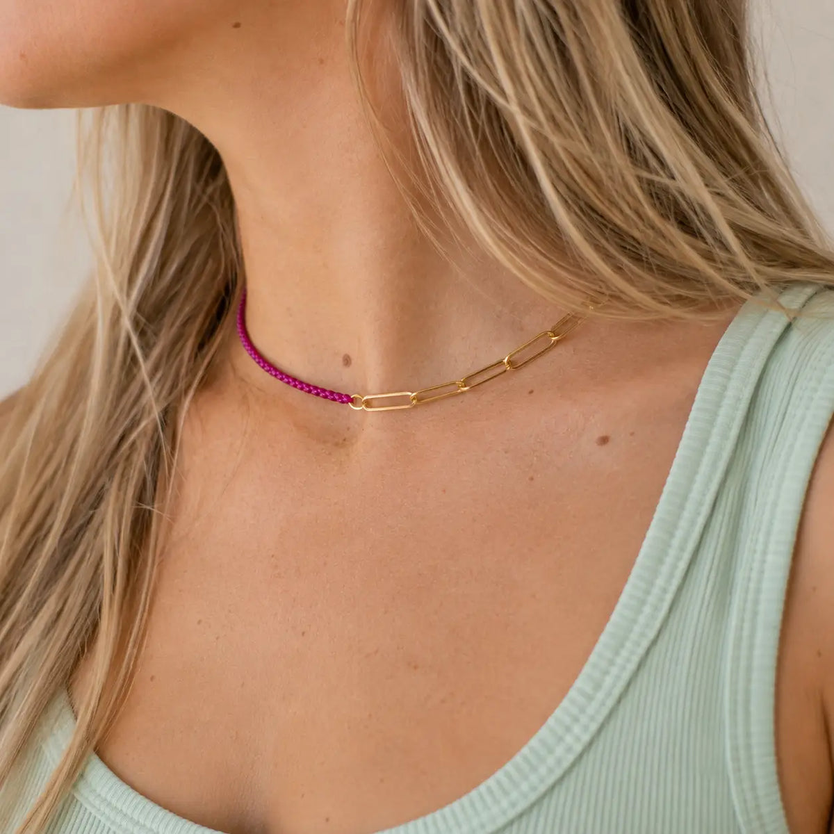 Two tone raspberry and gold plated chain necklace worn with a pale mint top.