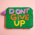 Green beaded zip pouch with ‘DON’T GIVE UP’ lettering in pink, orange and yellow and a purple pom pom zip detail.