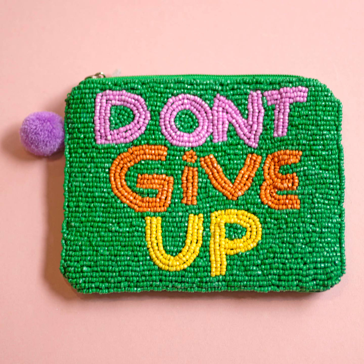 Green beaded zip pouch with ‘DON’T GIVE UP’ lettering in pink, orange and yellow and a purple pom pom zip detail.