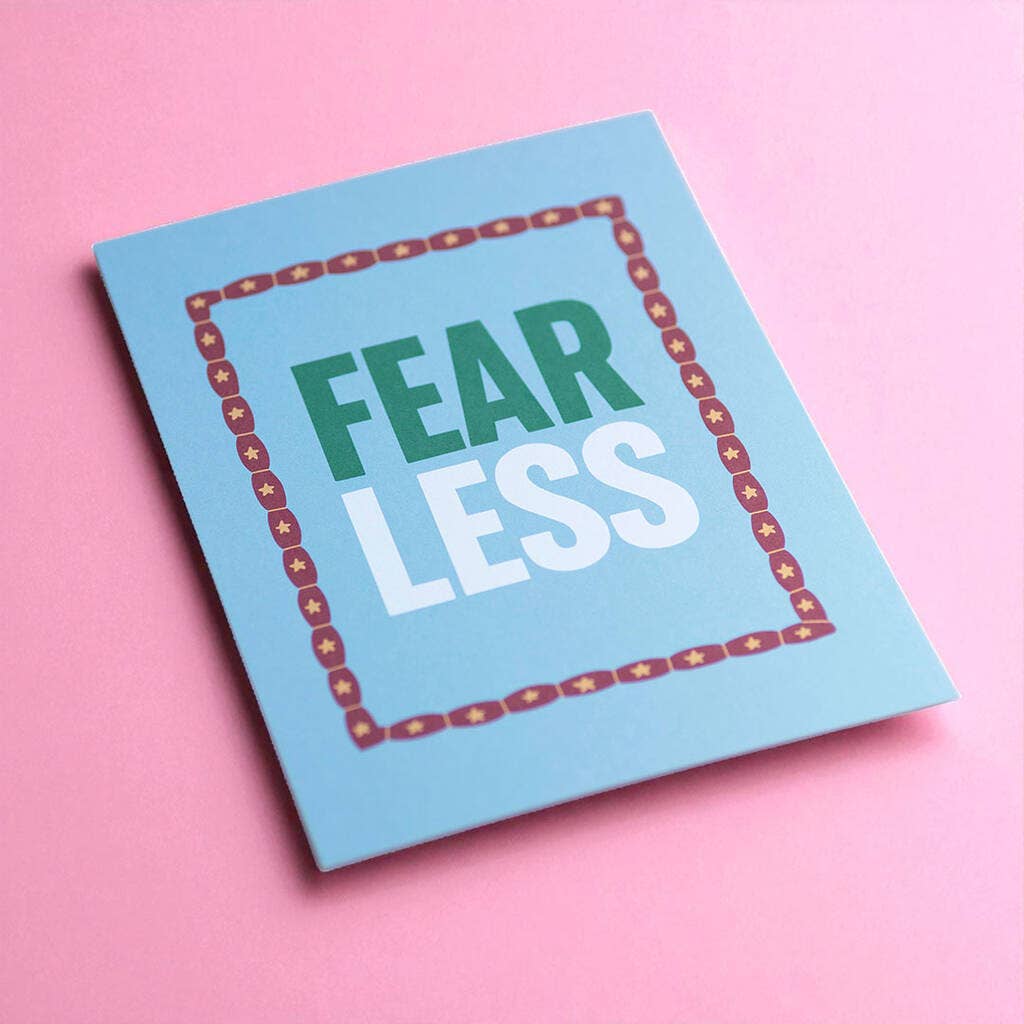 Colourful Fear Less A5 motivational print with bold lettering and star border, photographed against a bright pink background.