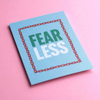 Colourful Fear Less A5 motivational print with bold lettering and star border, photographed against a bright pink background.