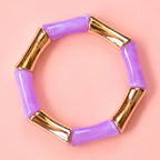 Lilac acrylic and gold bamboo inspired stretch bracelet on a pale pink background.