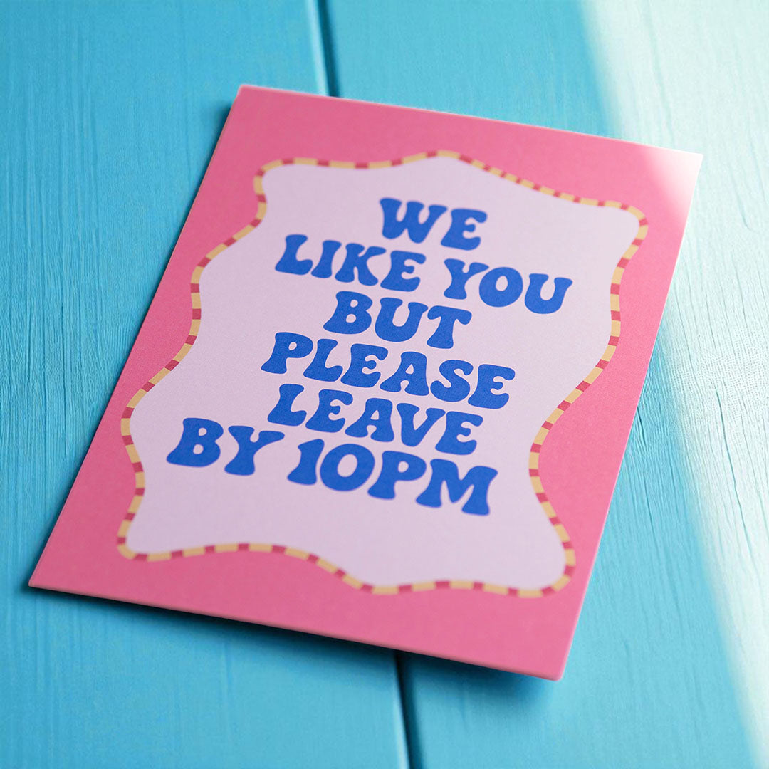 Playful We Like You But Please Leave By 10PM A5 print with retro blue lettering on a pink design.