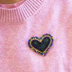 Purple and green beaded heart brooch pinned to a pink knitted jumper.