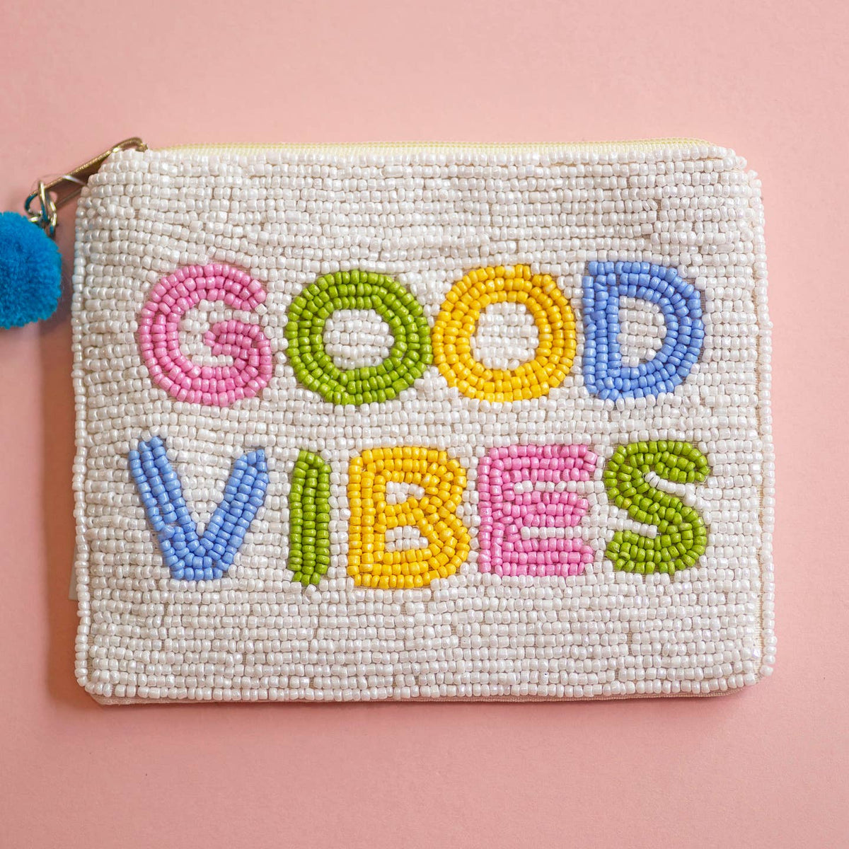 Beaded zip pouch with colourful ‘Good Vibes’ lettering in pink, green, yellow and blue, with a blue pom pom zip pull.