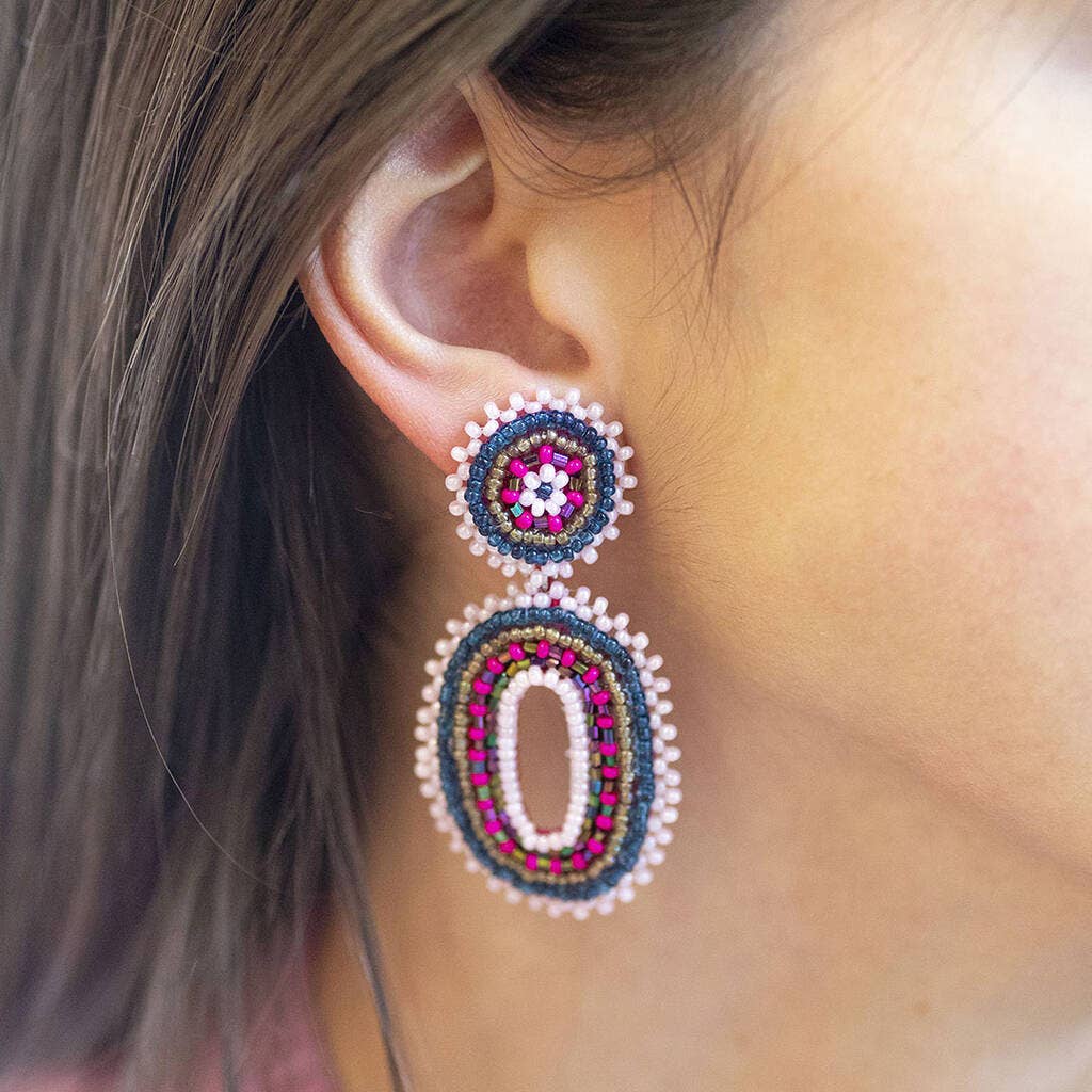 Pink and blue beaded oval statement earring worn on the ear, showing the colourful layered design.