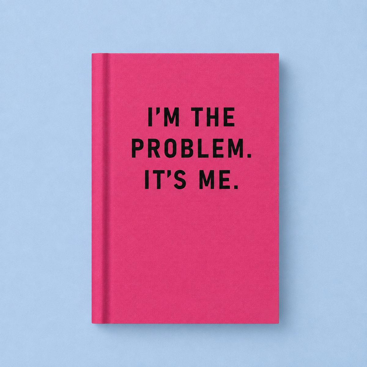 Bright pink A7 fabric hardback notebook with black I’m The Problem It’s Me text on a pale blue background.