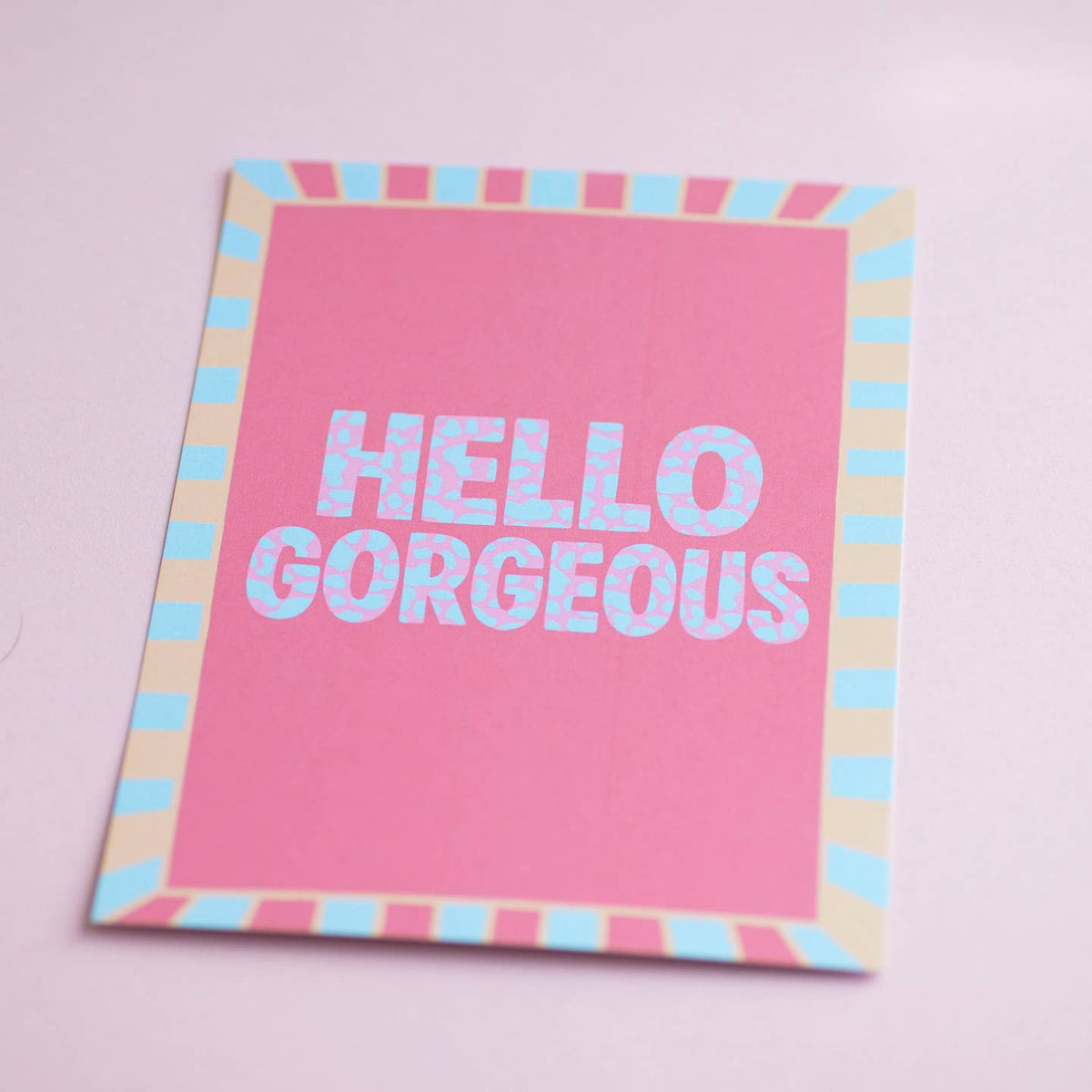 Colourful Hello Gorgeous A5 art print with bold patterned lettering and a playful pink, blue and peach striped border.