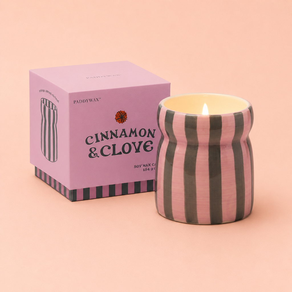 Cinnamon and Clove soy wax candle in a pink and deep green striped ceramic vessel beside its pink presentation box.