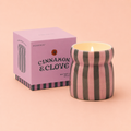 Cinnamon and Clove soy wax candle in a pink and deep green striped ceramic vessel beside its pink presentation box.
