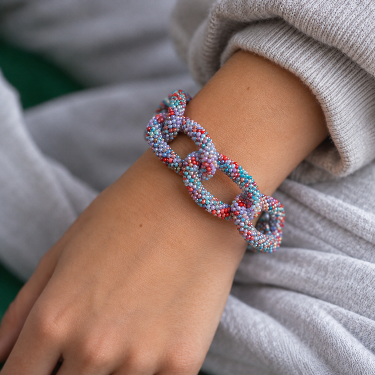 Blue mix chunky beaded chain bracelet worn on the wrist showing its colourful textured interlocking links.