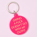 Hot pink round keyring with pale yellow Giving a Fuck Doesn't Go With My Outfit lettering and silver-tone keyring.