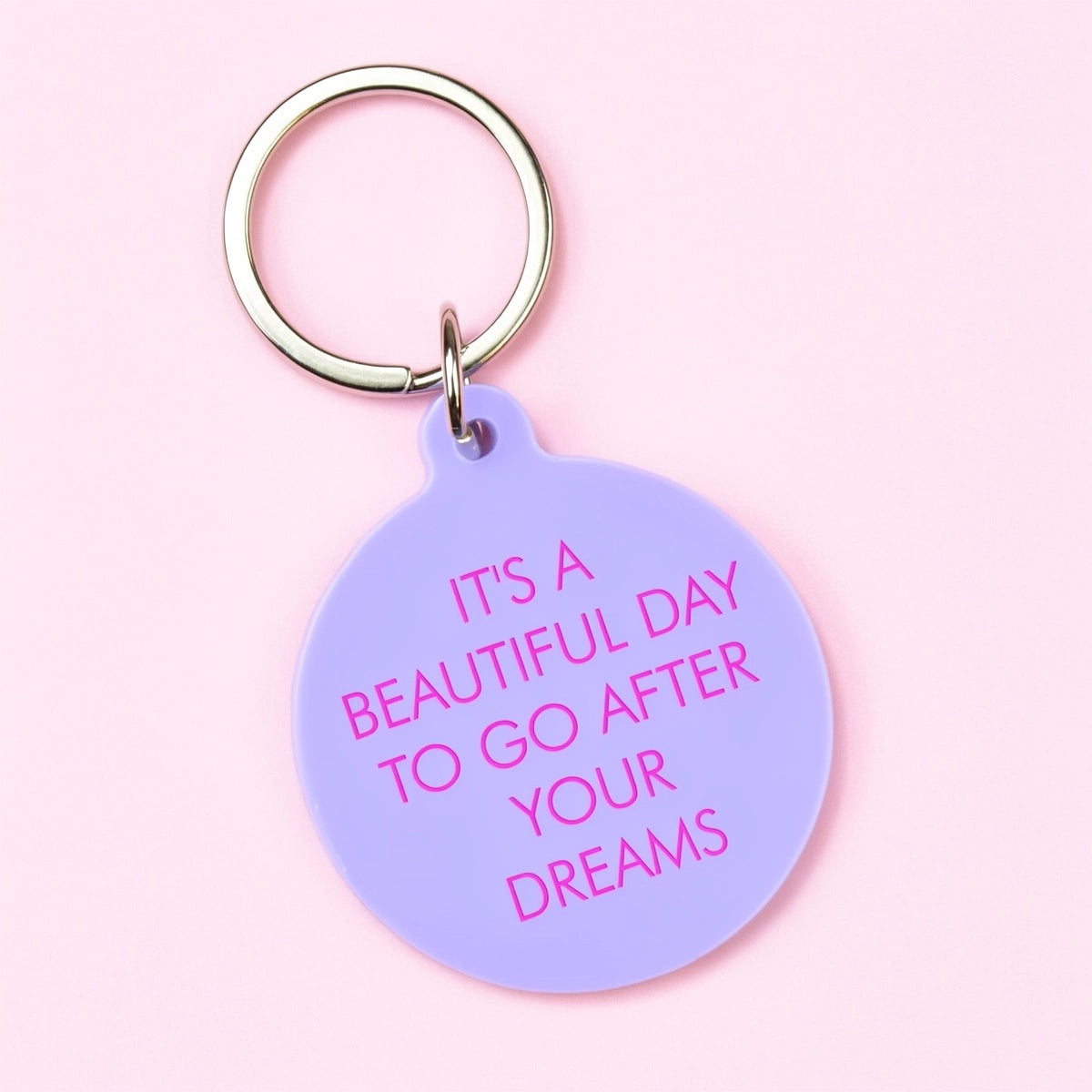 Lilac round statement keyring with pink It's a Beautiful Day to Go After Your Dreams lettering and silver-tone keyring.