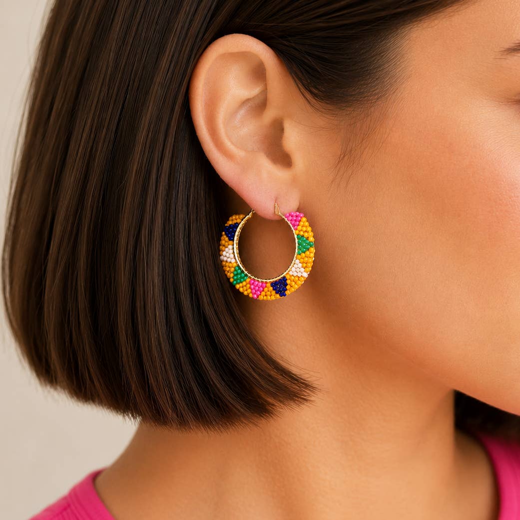 Yellow multicolour beaded hoop earring worn on the ear, showing the statement hoop size and colourful beadwork.
