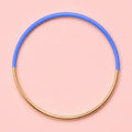 Blue dip enamel stacking bangle with a polished gold tone finish on a pale pink background.
