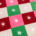 Close up of the soft pink, red, green and cream checked fabric with white starburst design.