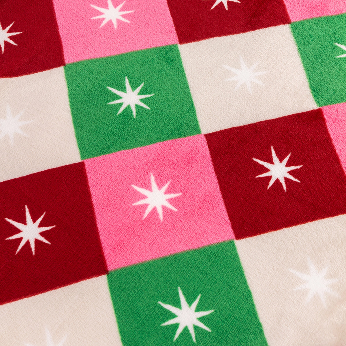 Close up of the soft pink, red, green and cream checked fabric with white starburst design.