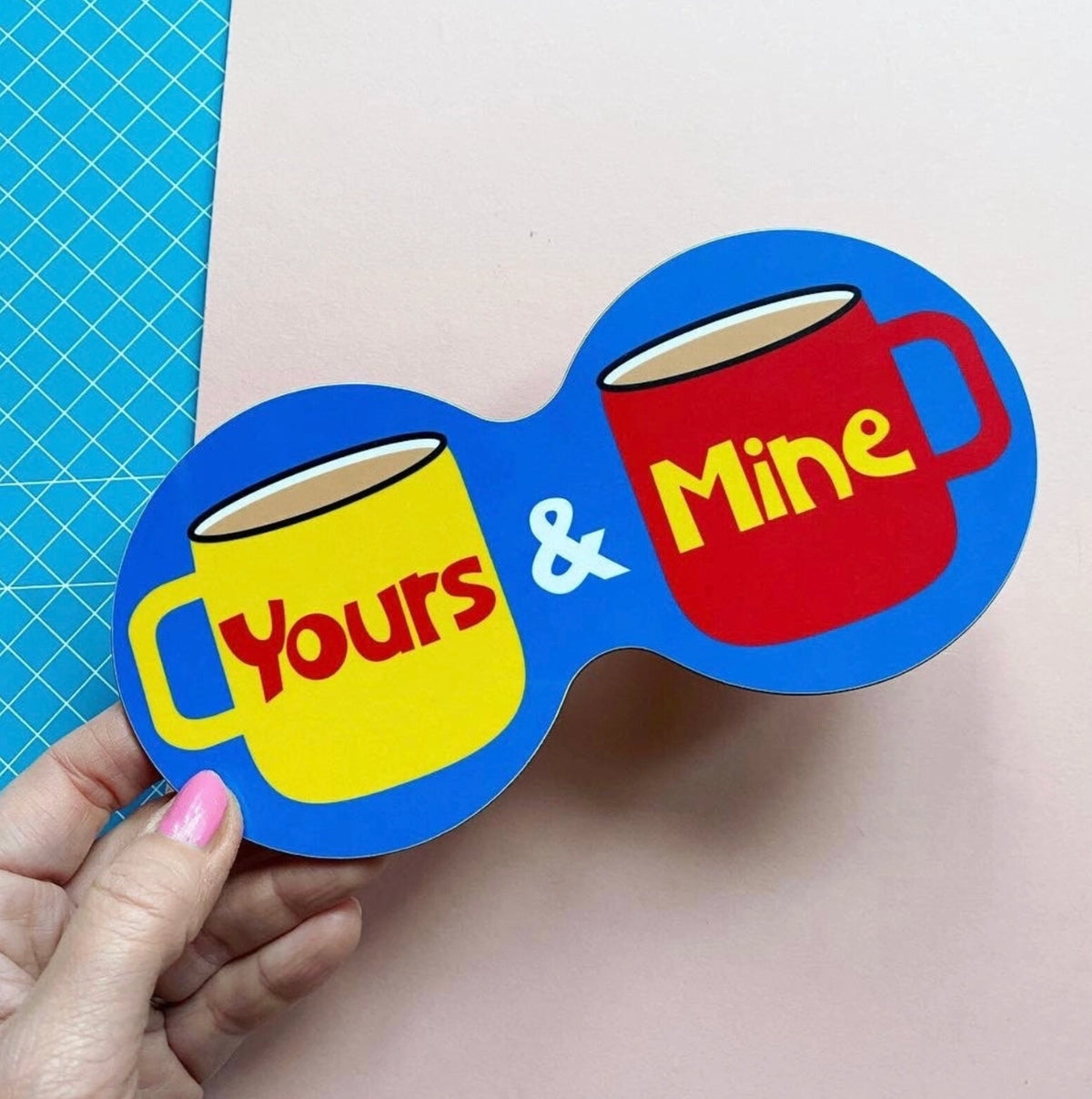 Bright blue Yours and Mine double coaster with illustrated yellow and red mugs and colourful retro lettering.