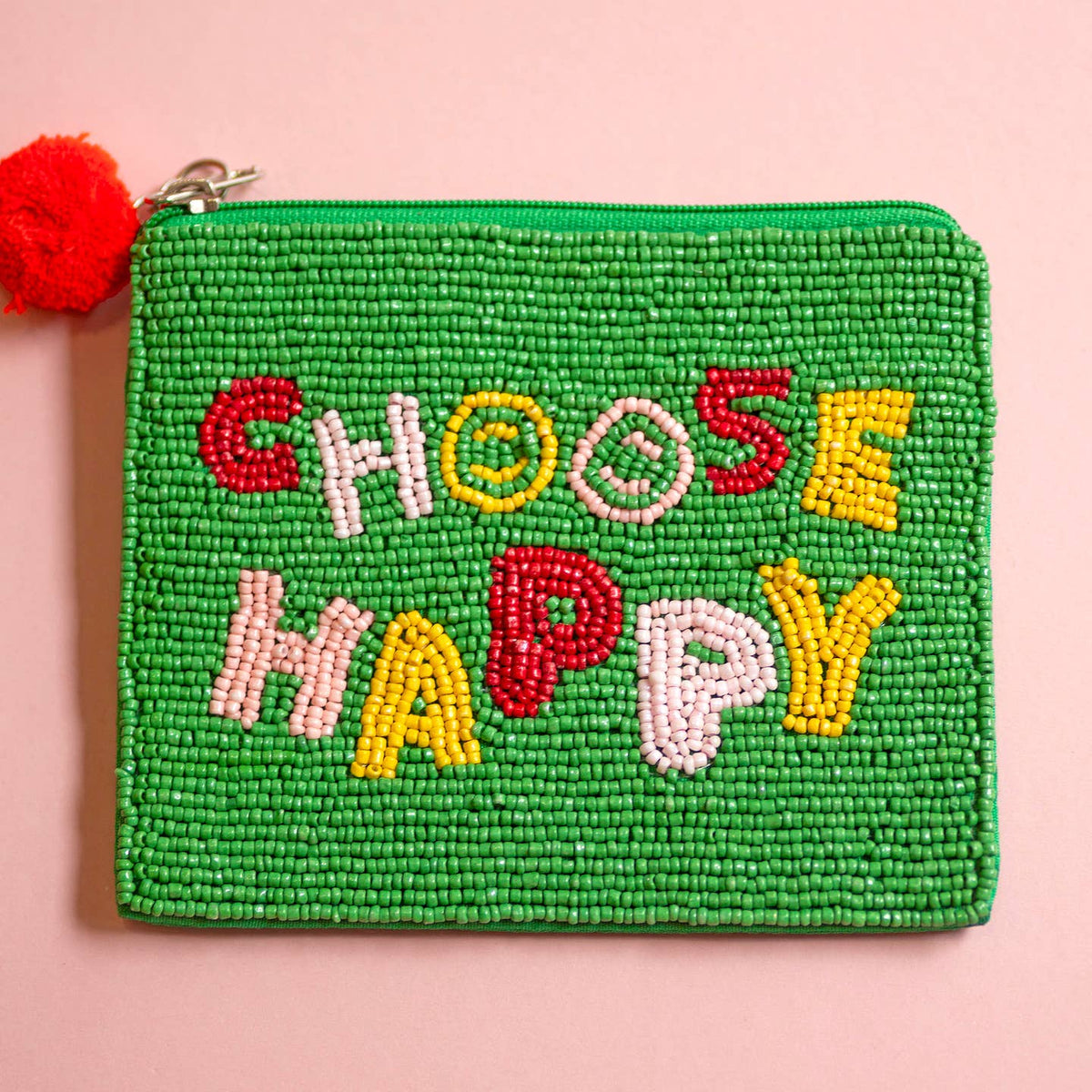 Green beaded zip pouch with colourful ‘CHOOSE HAPPY’ lettering in red, pink and yellow and a bright red pom pom zip pull.