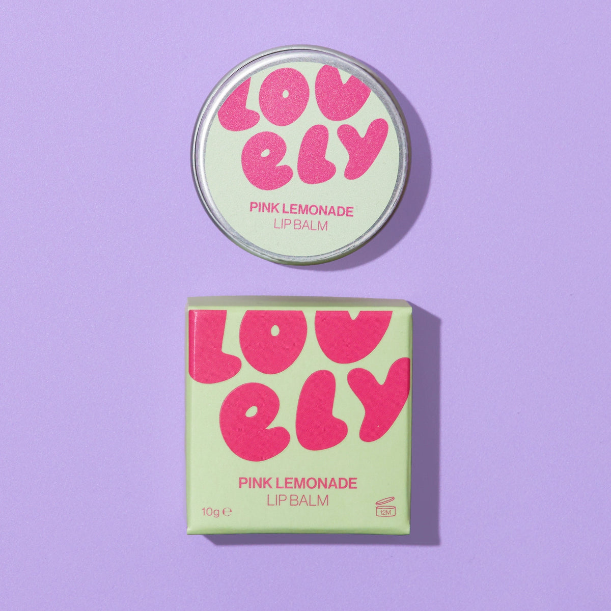 Pink Lemonade Lip Balm 10g tin and colourful box photographed on a lilac background.