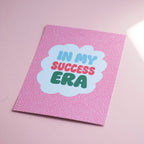 Cheerful In My Success Era A5 print with colourful retro lettering and a white scalloped centre on a pink patterned background.