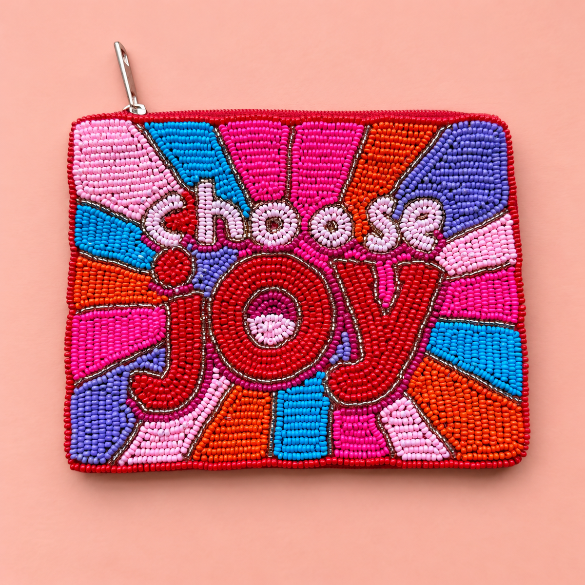 A square zippered pouch decorated with colorful beaded geometric patterns and the words 'choose joy' in raised lettering, shown on a solid peach-pink background.