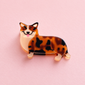 Corgi shaped acrylic claw hair clip in warm brown, black and cream tones on a soft pink background.