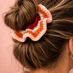 Pumpkin Spice handmade crochet scrunchie in orange, cream, pink and raspberry worn around a brunette bun.