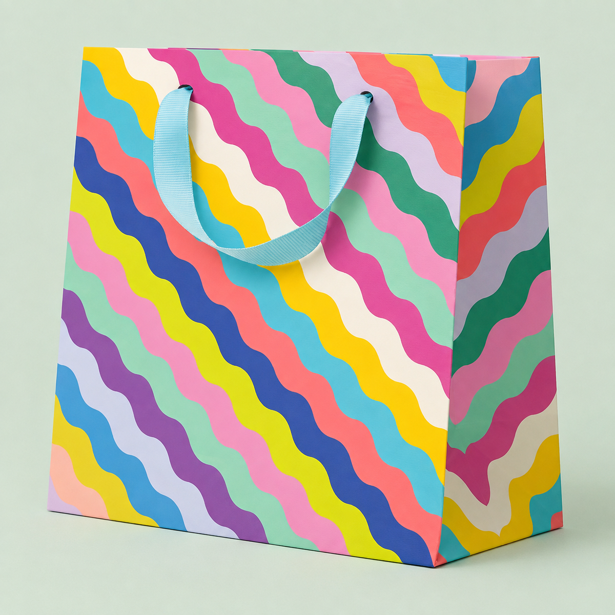 Colourful square gift bag with wavy rainbow stripes in pink, blue, green, yellow and purple with blue ribbon handles.