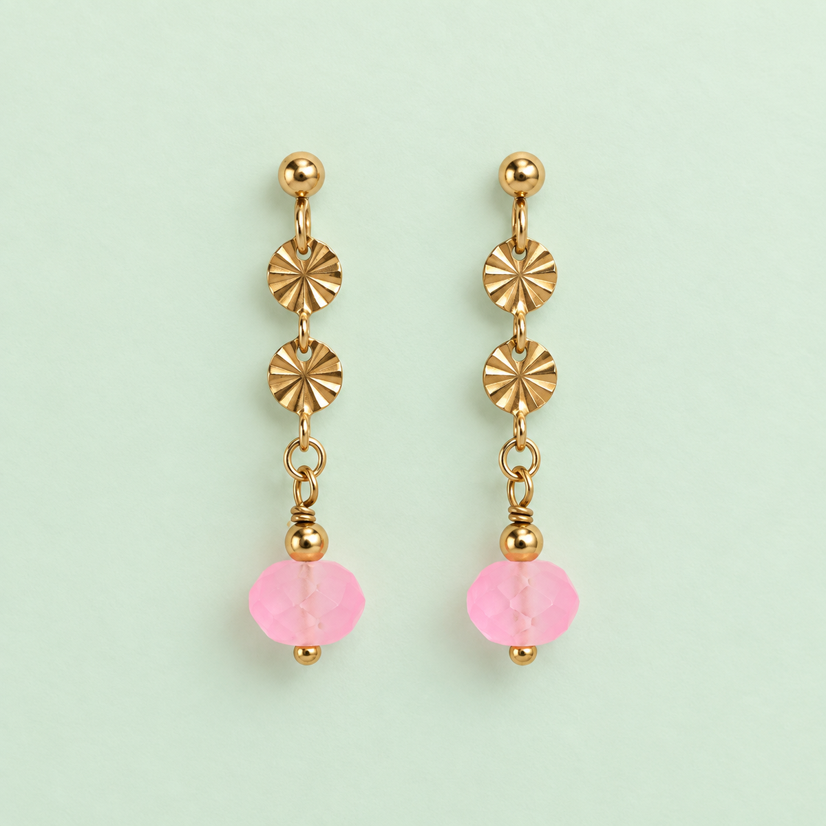 Pair of limited edition gold plated drop earrings with textured discs and frosted neon pink faceted glass beads on pale mint background.
