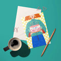 Colourful It’s Your Cake Day birthday card with illustrated cake, candles and yellow checked background styled with envelope and coffee.